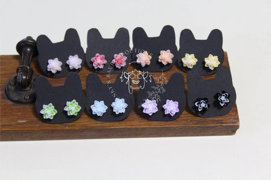 Colorful floral earrings displayed on black cat-shaped cards.